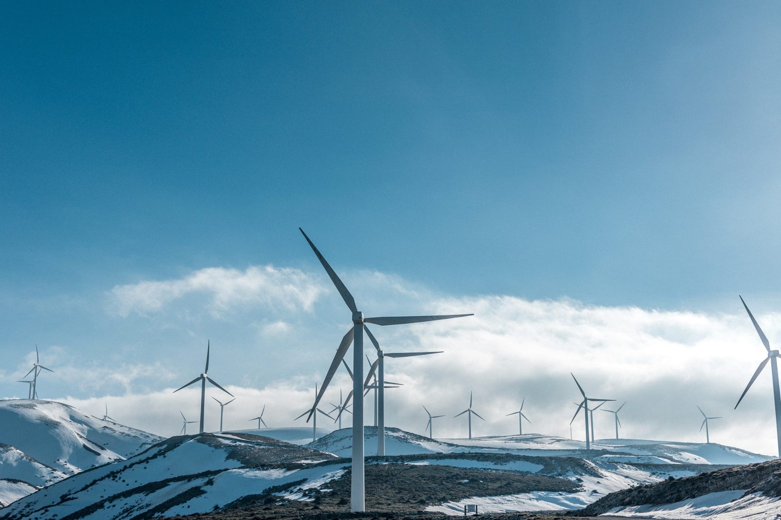 Windräder auf verschneiten Hügeln unter blauem Himmel