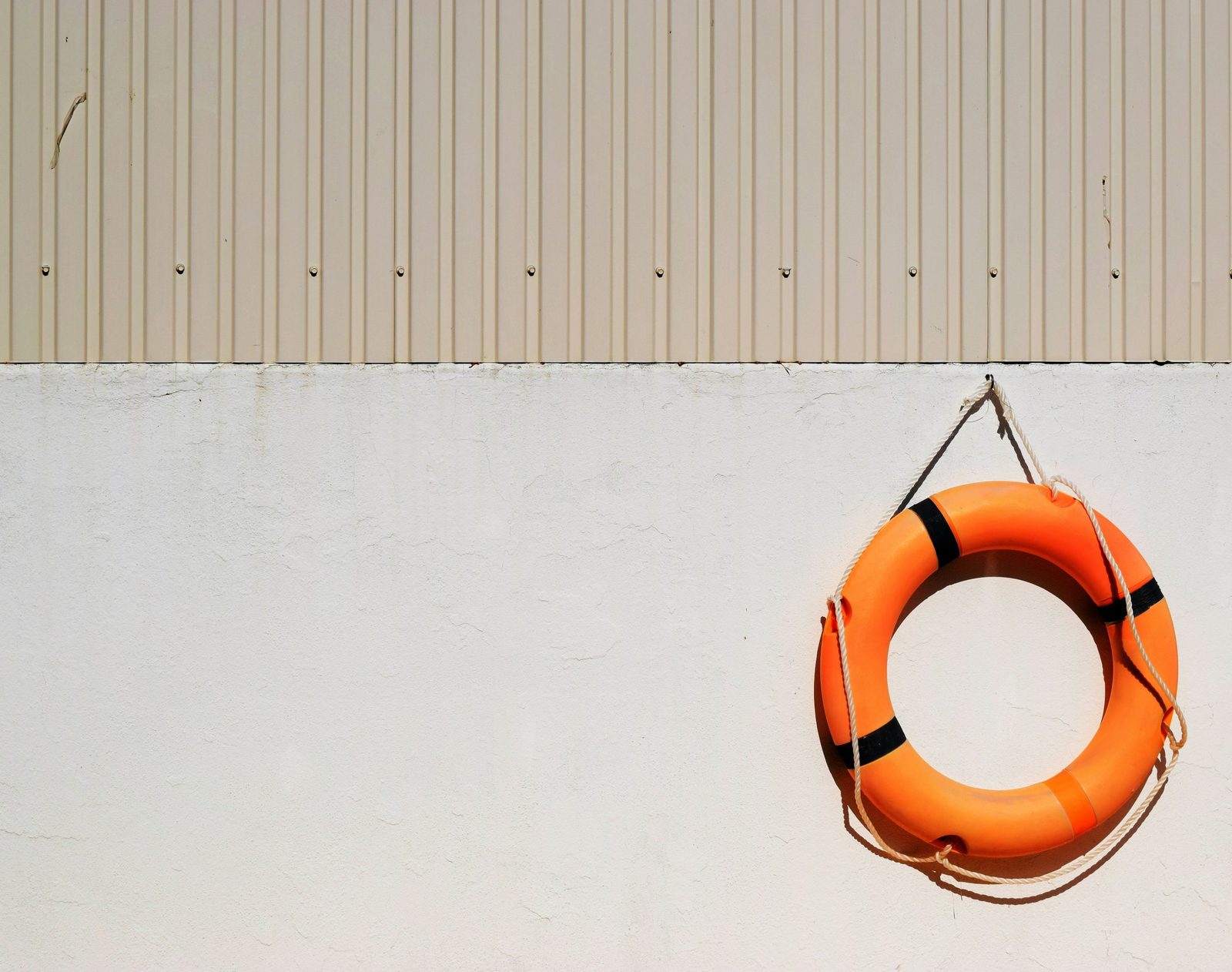 Orangefarbener Rettungsring an einer hellen Wand